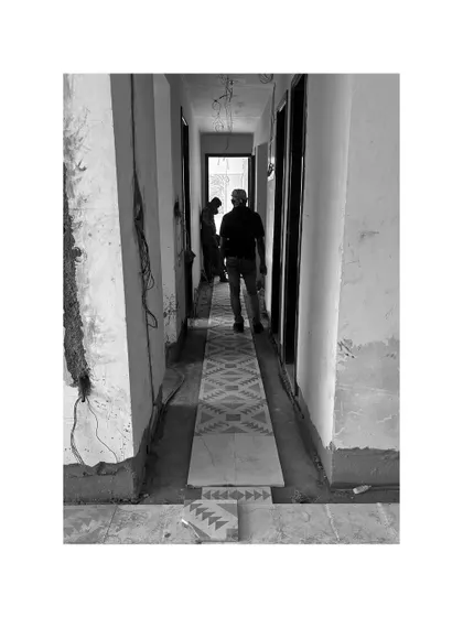 A patterned tile runner being installed in a hallway. Even in the midst of construction, the design begins to emerge.
