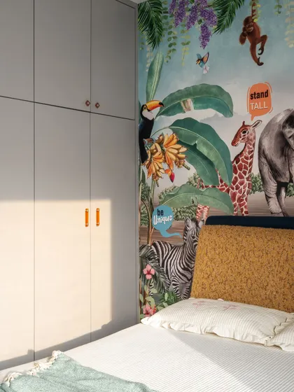 A detail shot of the vibrant jungle wallpaper next to the sleek, gray wardrobes. The contrast highlights the playful theme while showing how we integrate ample storage seamlessly into the design.