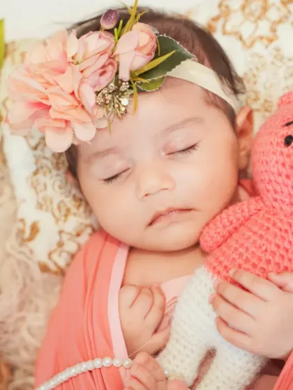 A close-up portrait of a newborn girl, complete with a floral headband and a cuddly teddy. These props are part of my collection and available for your session.