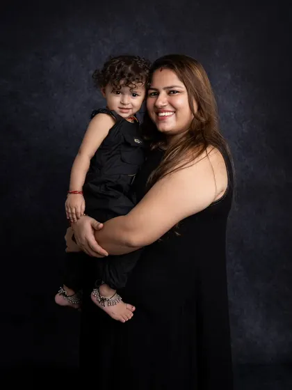 A lovely mother and child portrait. The simple dark background and coordinated outfits keep the focus on their happy expressions and close bond.