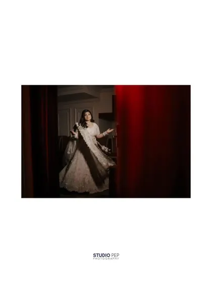 A creative, through-the-curtain shot of the bride, Shalini. This artistic framing adds a sense of mystery and anticipation to her bridal portrait.