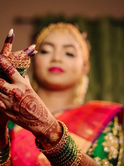 A close-up on the bride's hands, adorned with intricate henna and bangles. These details are an essential part of the bridal story.
