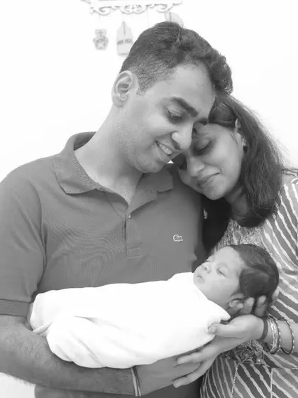 A peaceful moment captured in black and white. The parents hold their sleeping newborn, a beautiful, classic portrait of a new family.