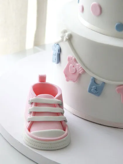 A close-up of the incredibly detailed, handcrafted pink fondant baby shoe.