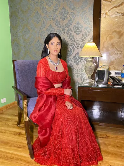 The full view of this stunning red cocktail ensemble. The makeup is timeless and sophisticated, ensuring she looks like a star.