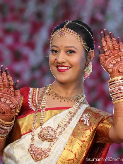 A radiant bride showcasing her full wedding look. Her detailed mehndi complements her jewelry and saree, completing her stunning bridal appearance.
