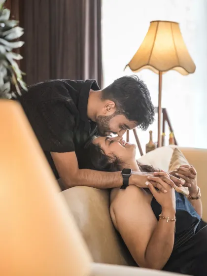A close, intimate portrait capturing a gentle forehead kiss. The warm lamplight creates a cozy and romantic mood, perfect for highlighting tender emotions.