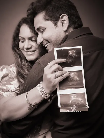 A treasured memory in sepia tones. This close-up shot captures the couple's joy as they look at their baby's first sonogram picture, creating a warm and nostalgic family portrait.