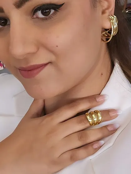 A close-up of our chunky gold-tone ring and matching hoop earrings. This set is perfect for creating a powerful, coordinated look that's both modern and timeless.