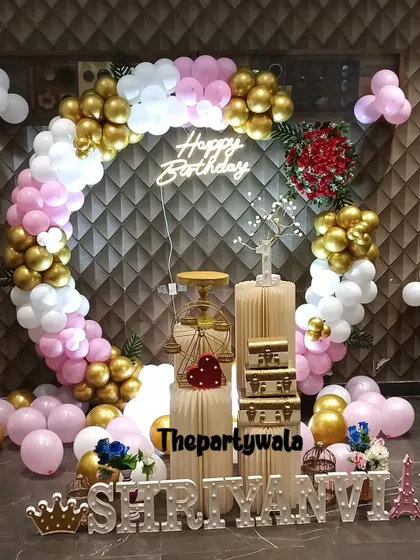 A beautiful ring decoration with pink, white, and gold balloons, accented with a red rose bouquet.