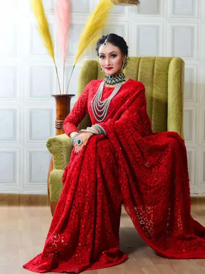 A full portrait of the client in her red saree. The makeup is classic and regal, perfect for a photoshoot or special occasion.