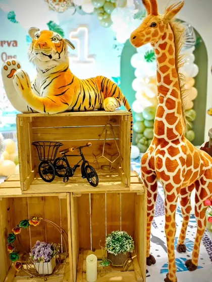 Lifelike props make all the difference. This detail shot from Atharva's 'Wild One' party shows a plush tiger and a tall giraffe figure, adding a realistic and impressive touch to the jungle theme decor.