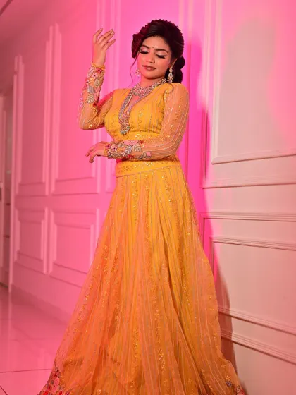 This full-length shot shows how the complete look comes together for a festive photoshoot. The makeup is balanced to complement the bright yellow lehenga and intricate jewellery, creating a harmonious and eye-catching image.