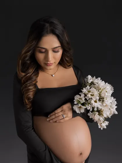 A classic and elegant portrait in a simple black gown, holding a bouquet of white flowers for a beautiful contrast.