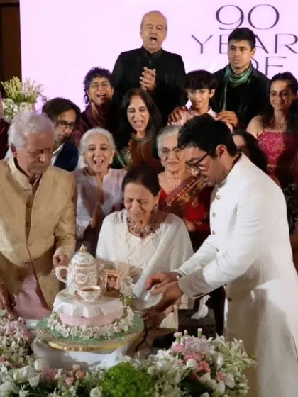 A beautiful family photo capturing the cake-cutting moment at Zeenat Hussain's 90th birthday party, with Aamir Khan and the whole family gathered around.