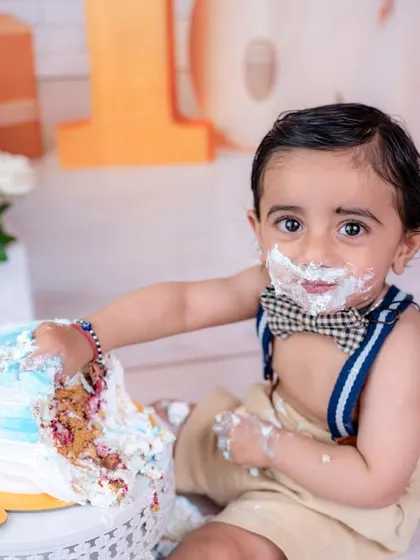 Getting hands-on with the birthday cake. This action shot captures the sensory experience and excitement of a first cake smash.