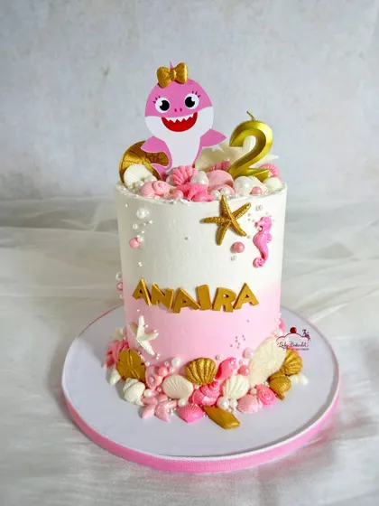 A pink Baby Shark cake! This design uses a pink and white ombre effect with gold and white shell details for a girly twist.