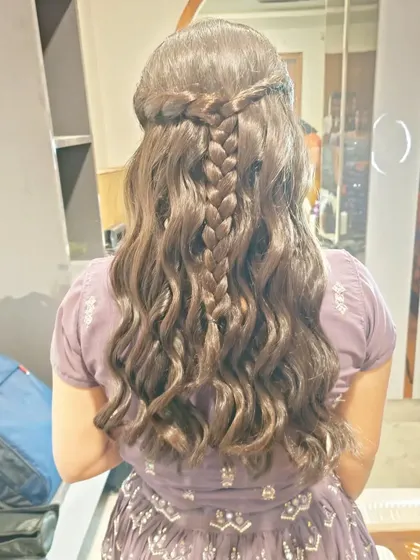A beautiful half-up hairstyle featuring a central braid and soft waves. This is a versatile look that can be worn for any wedding function.