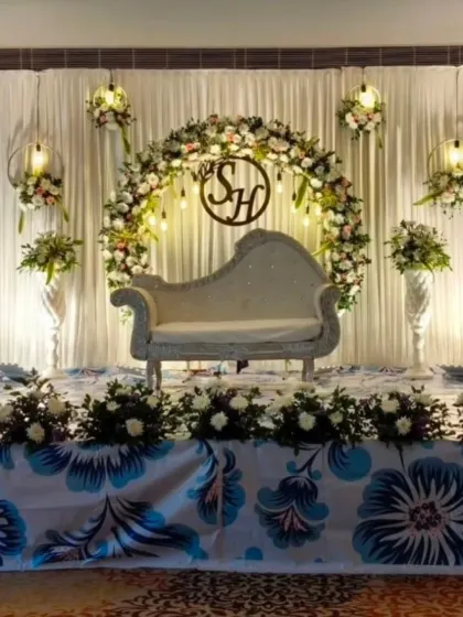 A sophisticated engagement stage with a floral ring, hanging birdcage lights, and a custom 'SH' monogram.