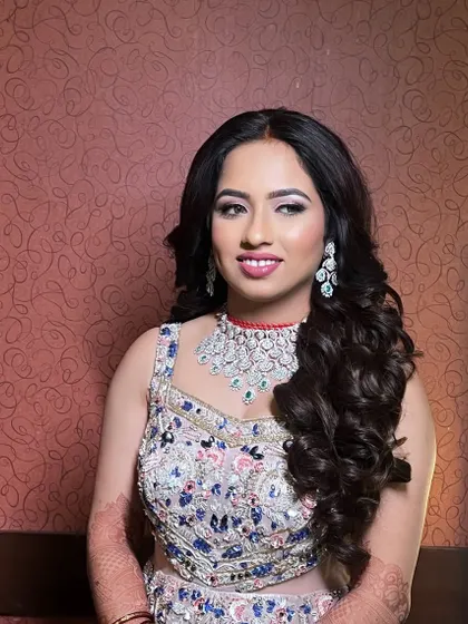 A beautiful reception look in a pastel floral gown. The makeup is soft and glamorous, with long, flowing curls.