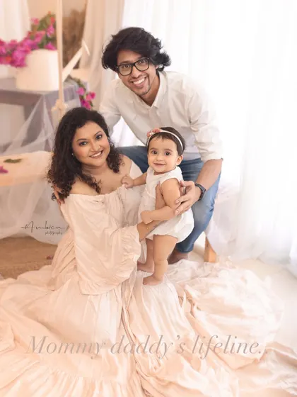 "Mommy and daddy's lifeline." This candid family portrait captures the pure joy and love that a child brings into a home, framed by soft, dreamy light.