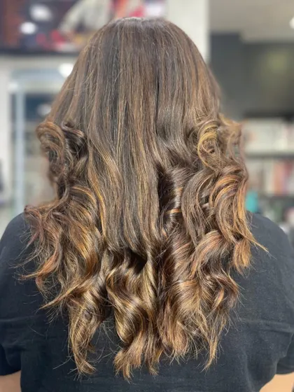 Beautifully styled curls on medium-length hair with warm, caramel highlights.