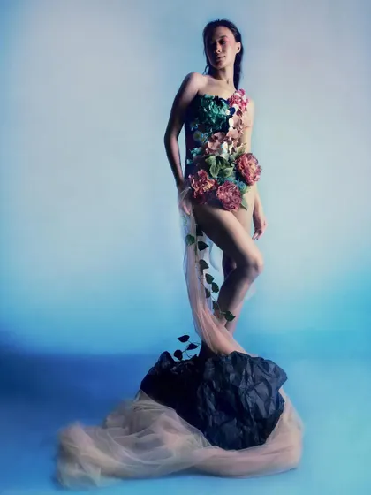 The model stands powerfully on a rock, draped in a sheer, flowing train. This composition transforms Ophelia from a tragic victim into a figure of strength, like the birth of Venus.