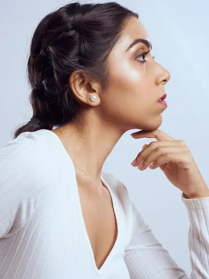 A profile view showing off a beautiful, radiant highlight on the cheekbones. The makeup is otherwise soft and minimal, with a berry-stained lip.