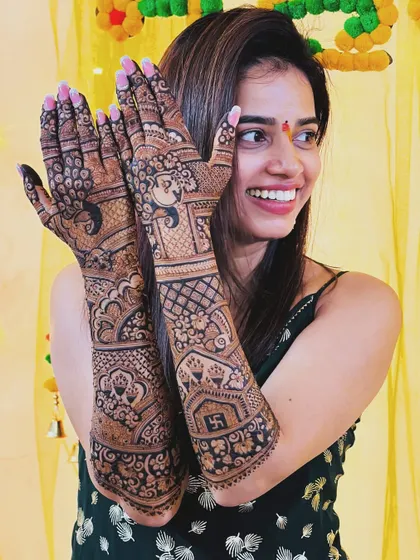 It's a special feeling to do the bridal mehendi for one of my own students. This image captures her joy, showcasing the intricate design that includes a Swastika for good fortune.