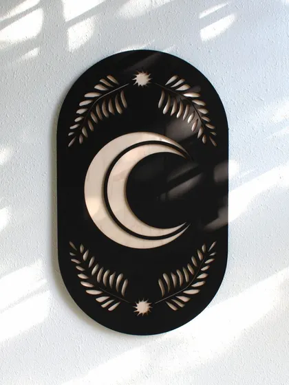This image shows the Botanical Moon Sign hung on a wall, with natural light casting soft shadows that highlight its 3D elements.
