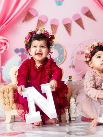 One year old and twice the fun! These twin girls are holding the 'ONE' letters to mark their big day.