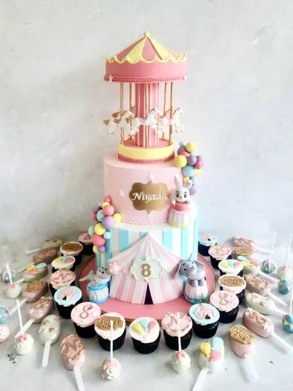 A carnival-themed dessert table is always so much fun. The centerpiece is a two-tiered cake with a working carousel on top, surrounded by colourful cupcakes, cake pops, and other treats.