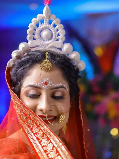 A serene portrait of a Bengali bride, her eyes closed, highlighting the intricate 'chandan' designs on her forehead.