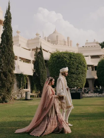 A couple walks through the manicured lawns of a heritage property, their pastel outfits complementing the old-world charm of the venue. This is a perfect example of a quiet, post-ceremony portrait.