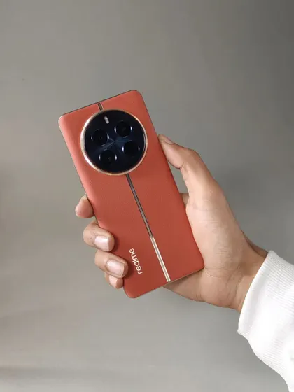A hand-held shot of the Realme 12 Pro+ Explorer Red edition. This image gives a sense of the phone's scale and premium leather-like texture.