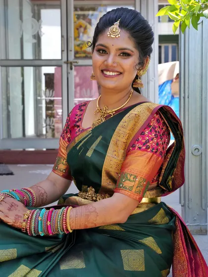 A full-length view of Meghana's look, showing how the makeup, hairstyle, and vibrant Kanchipuram saree come together for a complete and stunning bridal look.