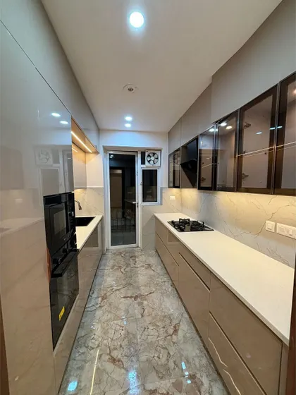 An elegant, factory-made parallel kitchen. The combination of glossy cabinets, a white countertop, and glass-fronted storage creates a sophisticated and highly functional workspace.