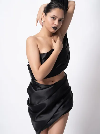 Another shot from the black satin series, showing a different pose. The simple white background makes the dark fabric and the model's form stand out.
