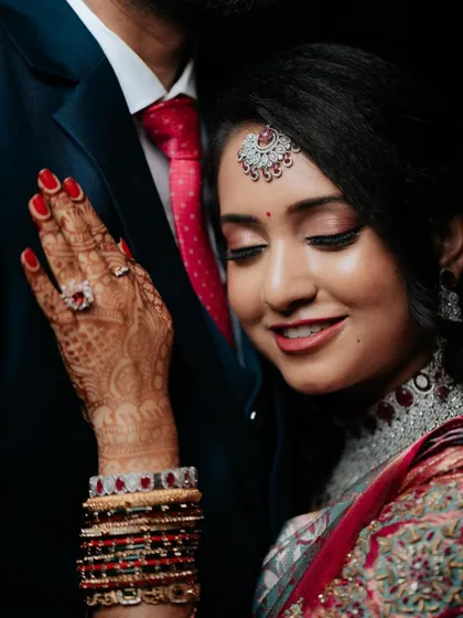 An intimate portrait of the bride resting her head on her groom's shoulder, her intricate henna and jewelry on full display.