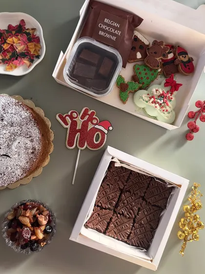 My Christmas goodie box is filled with festive treats. It includes sugar cookies, a Belgian chocolate brownie, hot chocolate mix, and a macaron.