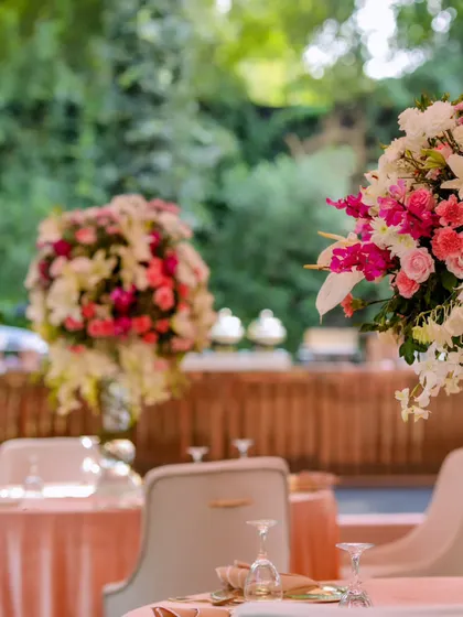 The lush floral centerpieces stand tall on the dining tables, adding color and life to the sophisticated pink and white decor scheme.