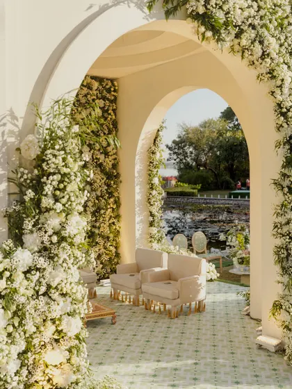 An archway completely covered in white flowers creates a stunning entrance to the mandap area. This immersive floral experience makes guests feel like they are stepping into a secret garden.