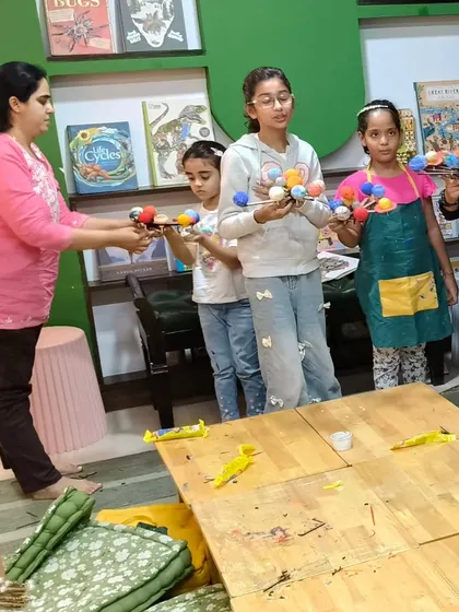 An instructor helps students arrange their newly made solar system models, a highlight of our astronomy-themed workshops.