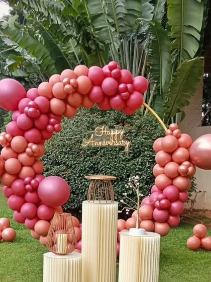 A beautiful anniversary decoration featuring a circular balloon arch in shades of rose and pink. This setup is perfect for an outdoor celebration.
