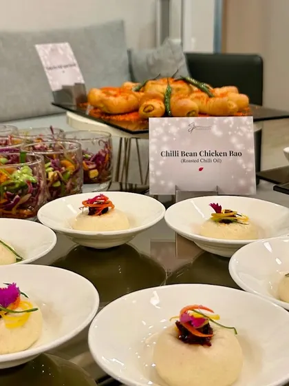 A spread of appetizers including Chilli Bean Chicken Bao and Asian salads, ready for guests to enjoy.