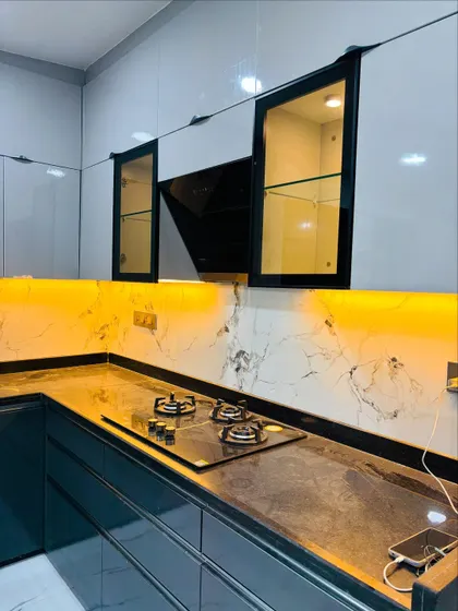 A close-up of the hob area, showing the sleek black chimney and the beautiful veining of the marble-patterned wall.