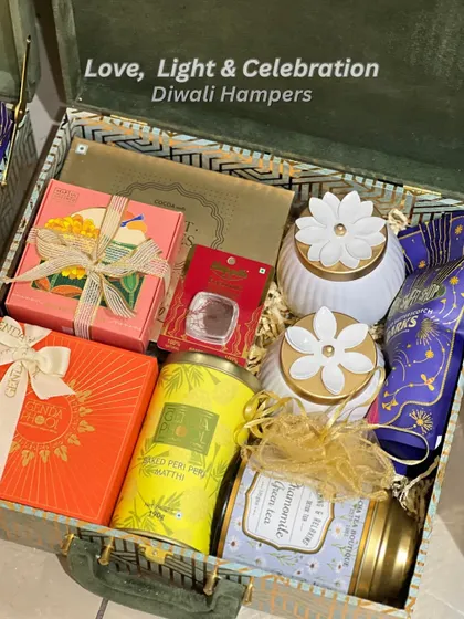 A luxurious Diwali hamper packed in a green velvet trunk. This "Love, Light & Celebration" box is filled with artisanal teas, premium sweets, and decorative candle holders.