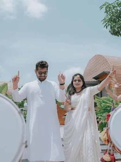 A fun shot of the couple dancing with dhol players, their hands in the air.