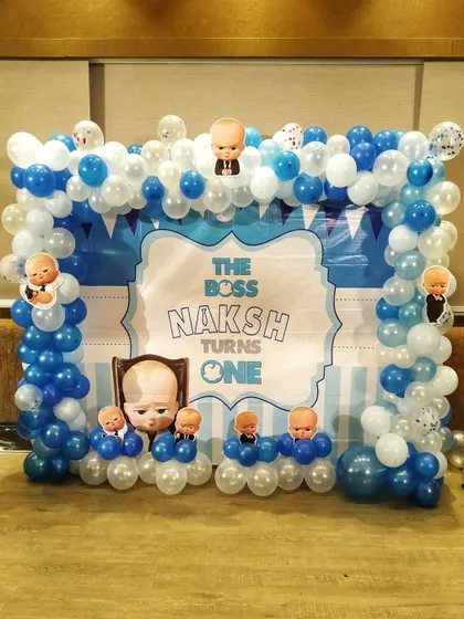 A Boss Baby balloon arch with a custom backdrop for a first birthday party, perfect for a cake-cutting ceremony.