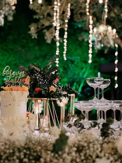 A dreamy cocktail party setup, with pastel blooms, chandeliers, and a beautiful cake table. The champagne tower adds a touch of glamour to the celebration.
